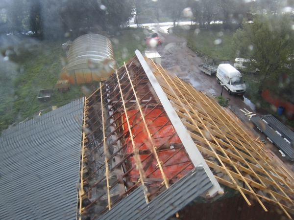 blik vanuit de natgeregende cabine van de hijskraan op de schuur